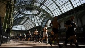 Athlètes Hyrox alternant course et ateliers fonctionnels dans un hall